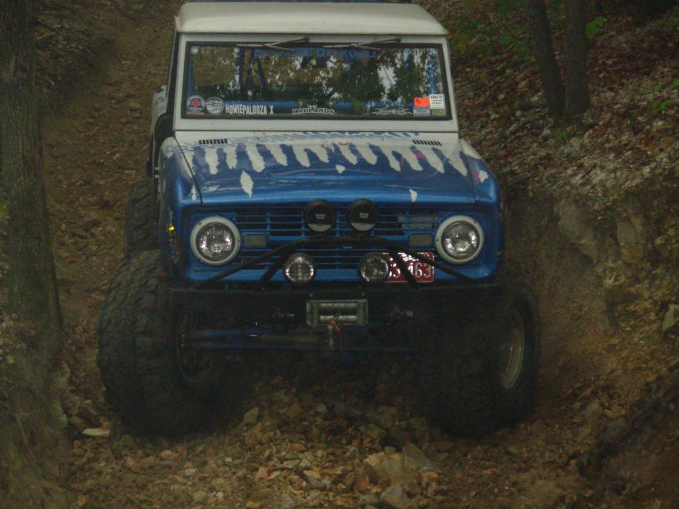 Blue and white flamed early Bronco with light bar and winch on rocky trail
