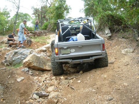 1983 Ford Bronco - A modified Ford Bronco tackles a challenging off-road course with spectators observing the action.