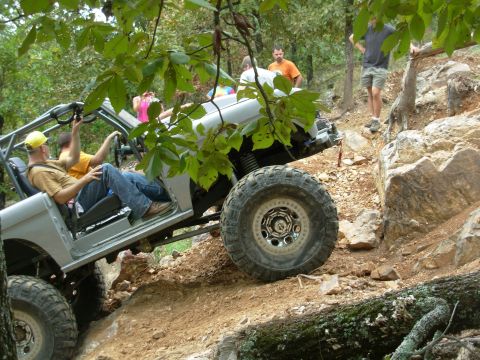 1983 Ford Bronco - An off-road vehicle navigates a challenging rocky terrain with several people observing.