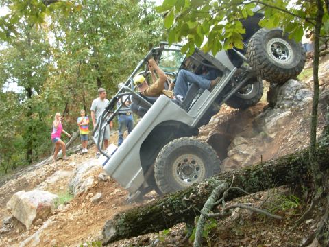 1983 Ford Bronco - A heavily modified off-road vehicle navigates a challenging rocky terrain with spectators observing the action.