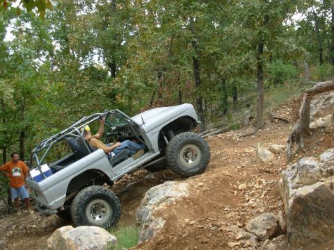 1983 Ford Bronco - This heavily modified Bronco is navigating a steep, rocky trail with a driver and passenger inside.