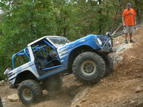 1983 Ford Bronco - Modified SUV with a roll cage navigates a challenging off-road trail.