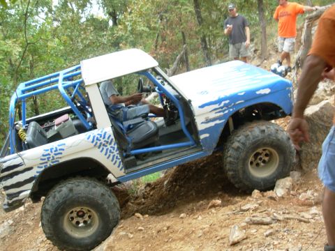 1983 Ford Bronco - This modified 1983 Ford Bronco navigates a challenging off-road course with its distinctive blue and white paint scheme and extensive roll…