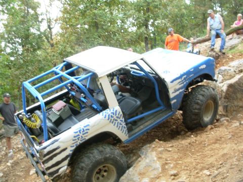 1983 Ford Bronco - This heavily modified SUV navigates a rocky trail with a custom roll cage and off-road tires.