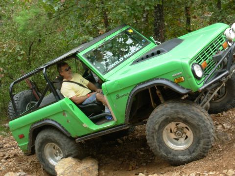 1983 Ford Bronco - A driver navigates a bright green Ford Bronco over a challenging, rocky trail.