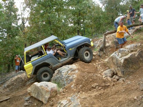 1983 Ford Bronco - This modified vehicle navigates a challenging rocky incline with spectators observing the ascent.