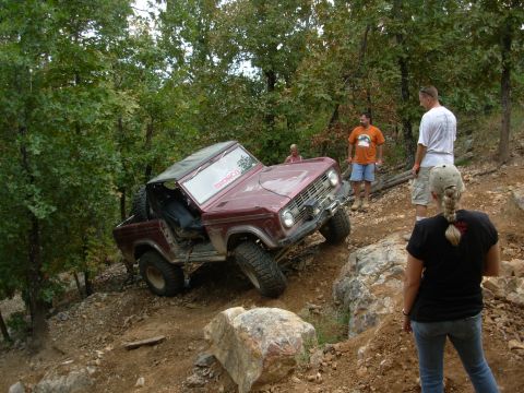 1983 Ford Bronco - A maroon Ford Bronco navigates a challenging off-road course with spectators watching.