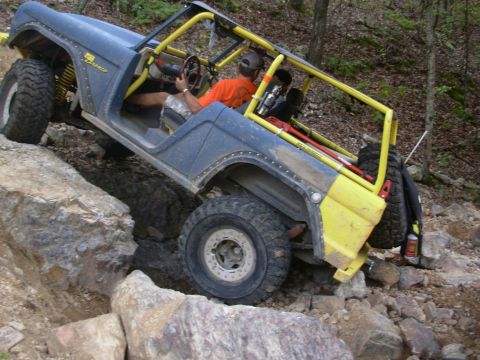 1983 Ford Bronco - Modified 1983 Ford Bronco navigating a rocky trail with its driver visible.