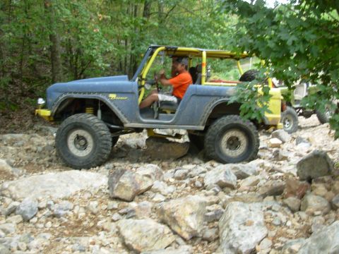 1983 Ford Bronco - A modified Ford Bronco navigates a rocky trail, with another vehicle visible in the background.