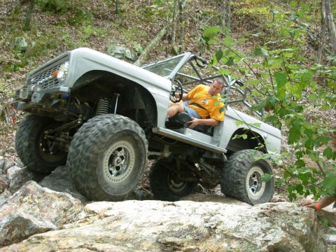 1983 Ford Bronco - Custom SUV navigating a rocky trail with a driver behind the wheel.