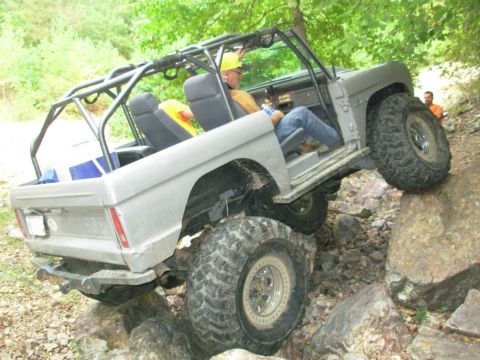 1983 Ford Bronco - Modified Ford Bronco with roll cage navigates rocky terrain off-road.