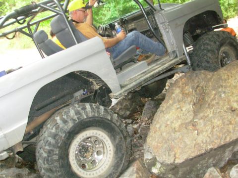 1983 Ford Bronco - A heavily modified off-road vehicle navigates a rocky terrain with a driver inside.