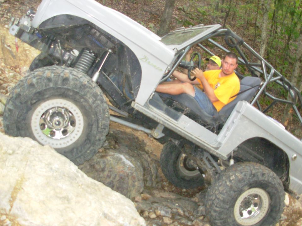 Doorless white Ford Bronco rock crawler with beadlocks climbing a boulder