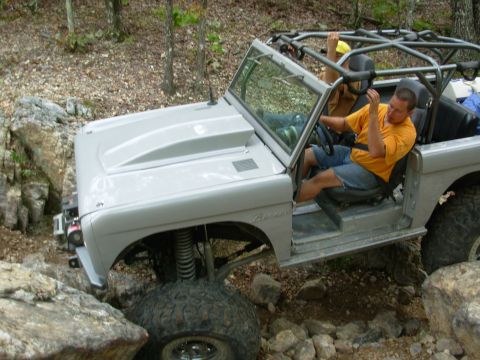 1983 Ford Bronco - Modified SUV with roll cage navigating rocky terrain off-road.