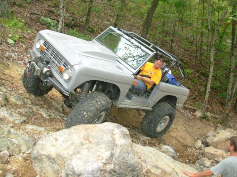 1983 Ford Bronco - A modified Ford Bronco navigates a challenging rocky trail with a driver behind the wheel.