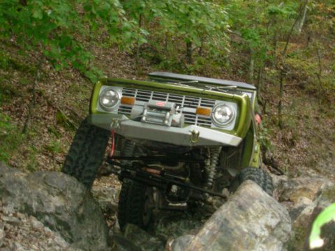 1983 Ford Bronco - Green 1978 Ford Bronco navigates a rocky trail with a winch attached.