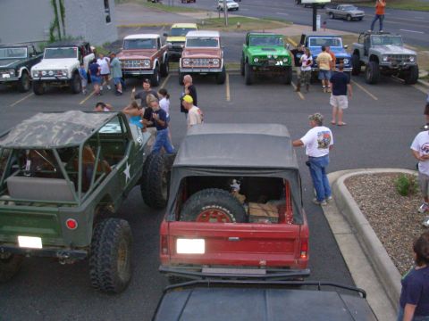 1983 Ford Bronco - A group of off-road vehicles, including a red Ford Bronco, are gathered in a parking lot.