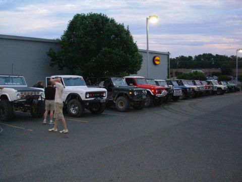 1983 Ford Bronco - A line of Ford Broncos are parked in a lot outside a building.