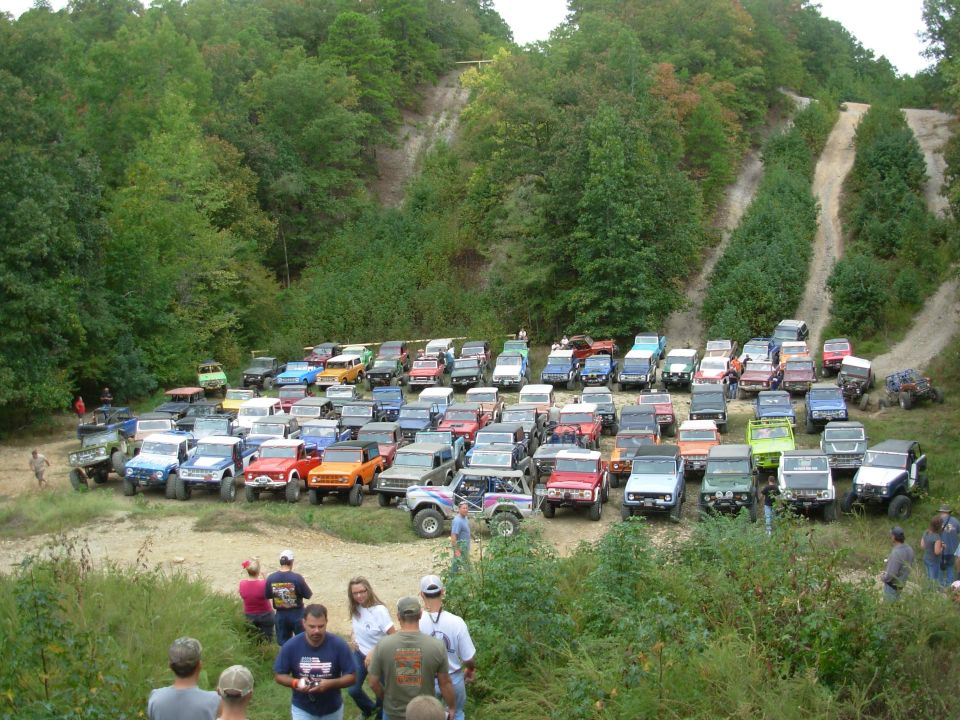 Dozens of lifted early Ford Broncos parked in rows at an off-road park group photo