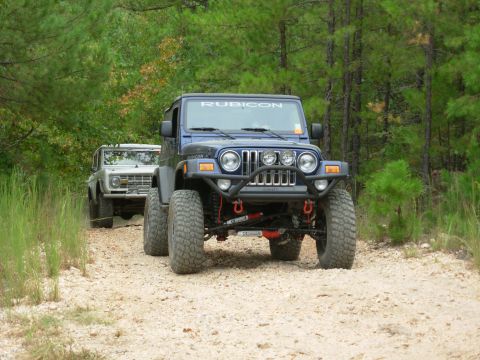 1983 Ford Bronco - A silver 1978 Ford Bronco leads a blue Jeep Rubicon on a gravel road through a wooded area.