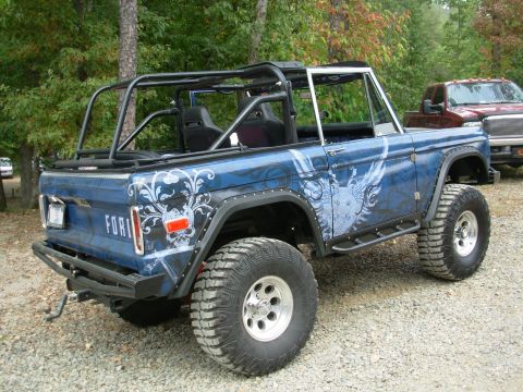 1983 Ford Bronco - This modified Ford Bronco features a custom blue paint job with skull and wings graphics, a roll cage, and large off-road tires.