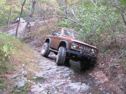 1983 Ford Bronco - Ford Bronco tackling a challenging off-road course in a wooded area.