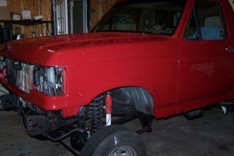1990 Ford Bronco - Front view of a red 1990 Ford Bronco undergoing work, with the grille missing.