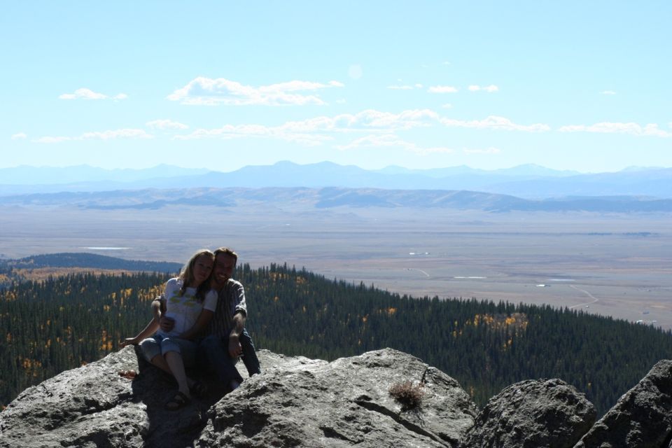 Couple on rocks overlooking a vast valley and mountains