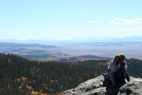1996 Ford Bronco - Couple enjoys a scenic view from a rocky outcrop, with a wide valley and distant mountains.