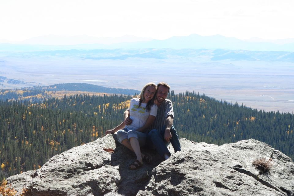 Couple sitting on a rock overlooking a valley and mountains