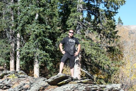 1996 Ford Bronco - Man poses for a photo in a rocky, forested area with pine trees.