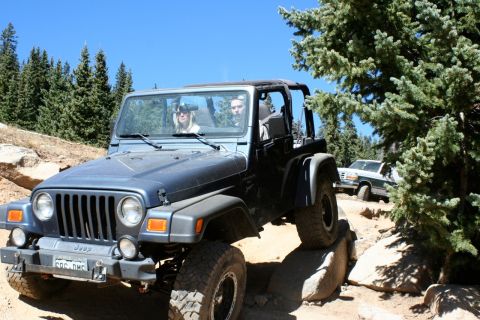 1996 Ford Bronco - A blue Jeep Wrangler tackles a challenging off-road path, with a second vehicle visible in the background.