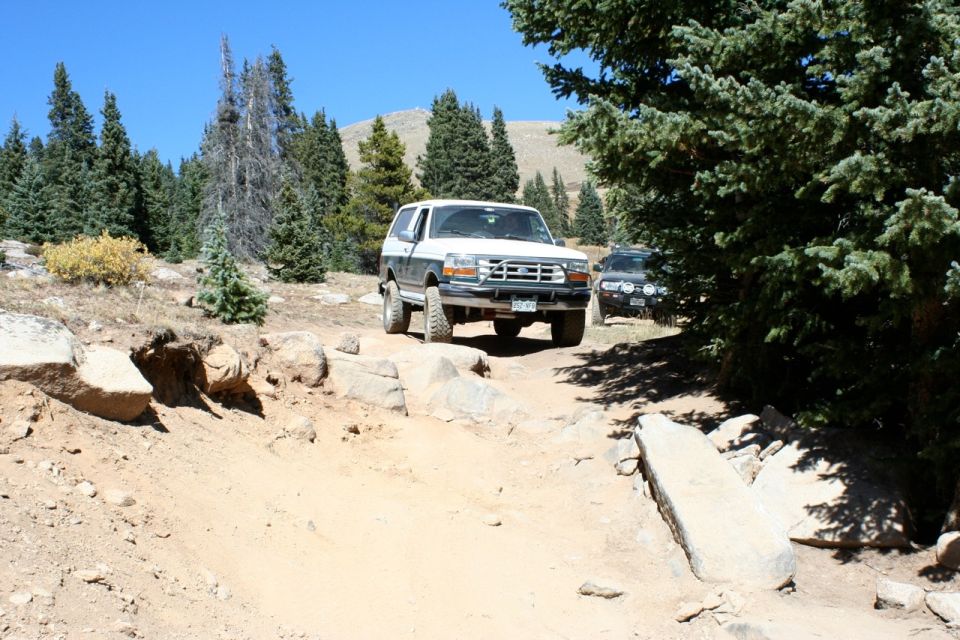 1996 Ford Bronco driving on a rocky dirt trail with another SUV behind it