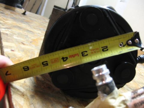1995 Ford Bronco - A black air compressor part is measured with a yellow tape measure, indicating approximately 4 inches.