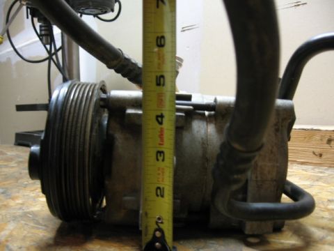 1995 Ford Bronco - A close-up view of an air conditioning compressor, showing its pulley and attached hoses.