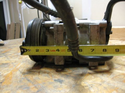 1995 Ford Bronco - A belt-driven air conditioning compressor is measured with a yellow tape measure, indicating approximately 5 inches.