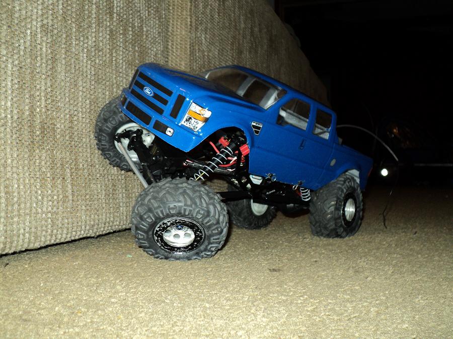 Blue 2008 Ford F-250 remote control truck with large tires, angled on a textured surface