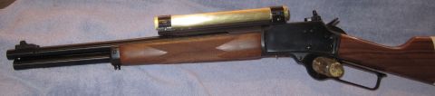 1990 Ford Bronco - A rifle with a wooden stock and a brass scope is shown from the side.
