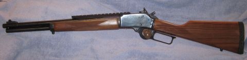 1990 Ford Bronco - A lever-action rifle with a wooden stock and a scope mount is shown from the side.