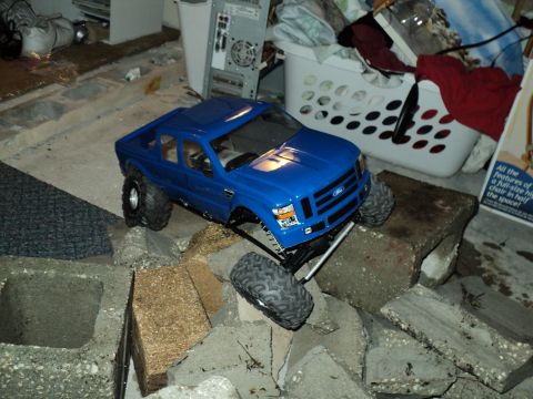2008 Ford F-250 - A blue remote-controlled truck is positioned on a surface made of concrete blocks and debris.