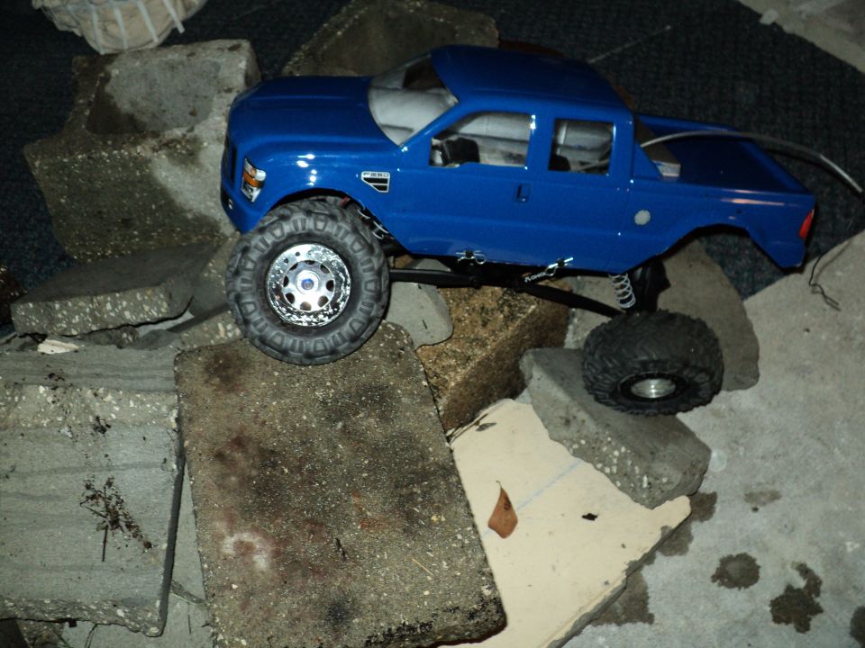 Blue 2008 Ford F-250 RC truck on concrete blocks, front 3/4 view
