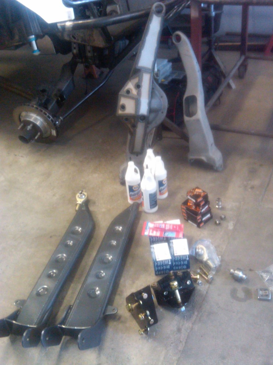 Off-road suspension components and bottles of fluid on a garage floor