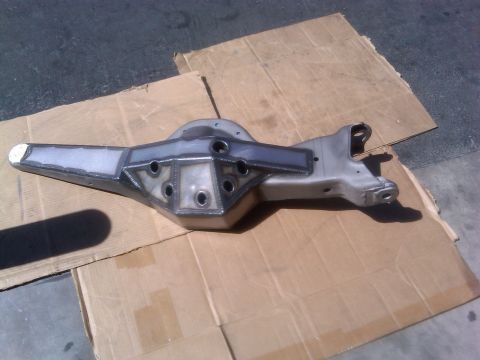 1986 Ford Bronco - Custom rear axle housing with reinforced center section and welded brackets, resting on cardboard.