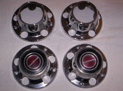 1990 Ford Bronco - Set of four chrome wheel center caps arranged on a light surface: two open-center caps for hub access and two closed caps with red center e…