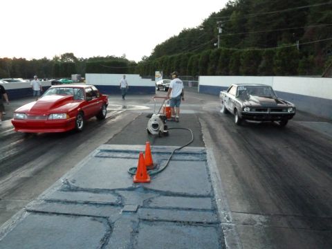 1992 Ford Mustang - A red drag car with a prominent hood scoop is on a race track, with another car to its right.