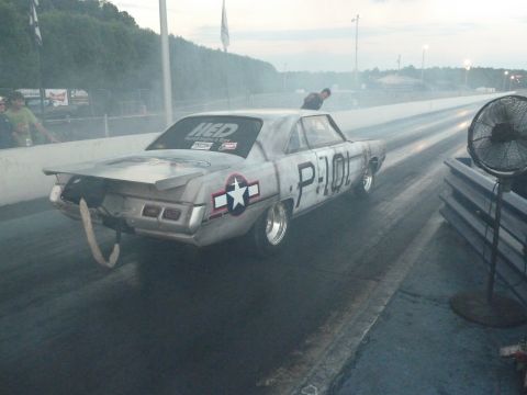 1992 Ford Mustang - A drag car with military-inspired paint and markings races down the track, kicking up smoke.