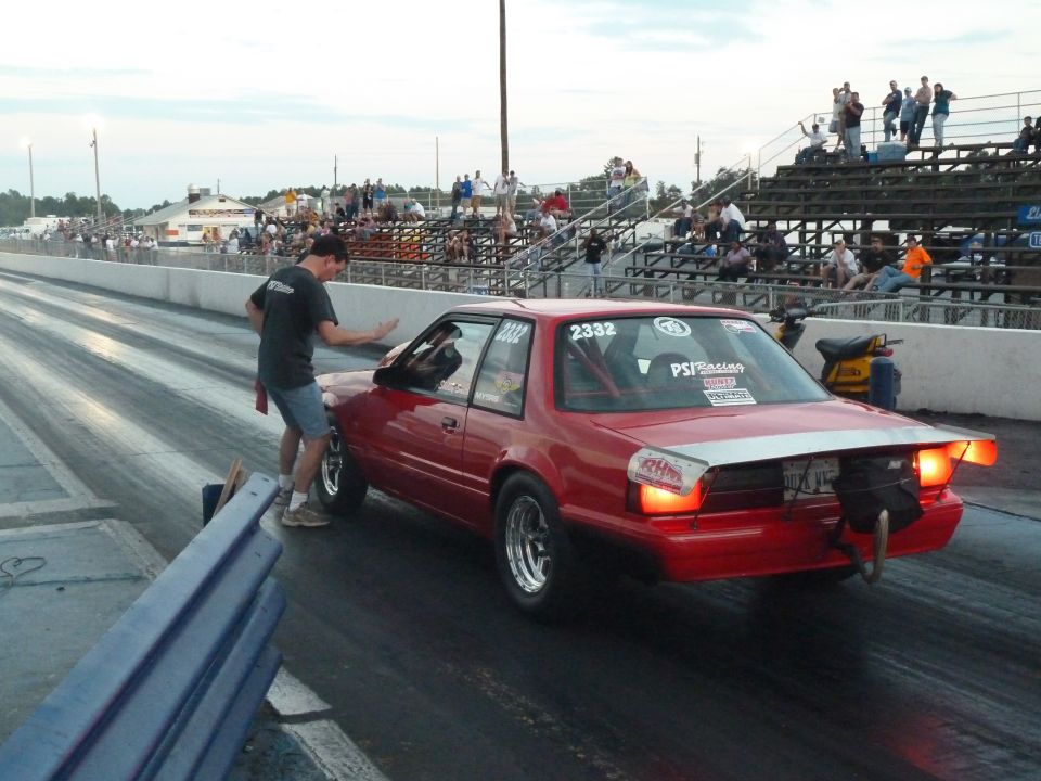 Red 1992 Ford Mustang drag car with racing decals on a track, driver's side visible