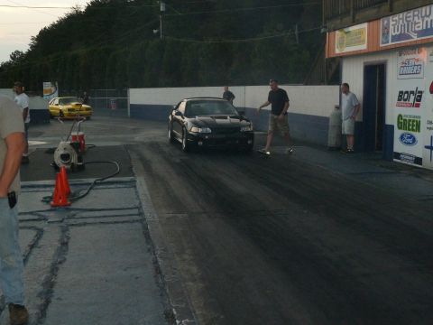 1992 Ford Mustang - A black Ford Mustang is on the drag strip, with a yellow car visible in the background.