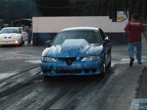 1992 Ford Mustang - A blue drag car with flame graphics sits on a track, with another car visible in the background.