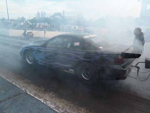 1992 Ford Mustang - A drag racing car with flame decals and a spoiler is on the track, producing smoke.